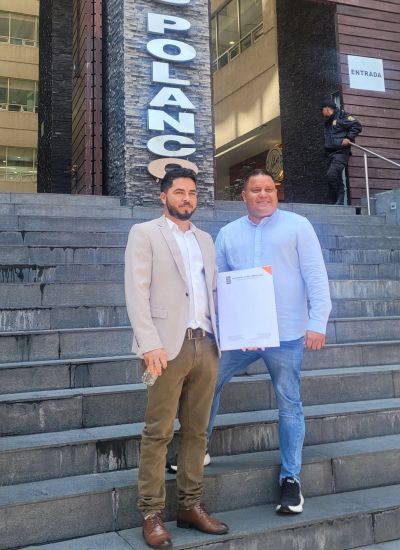 Two men pose at the entrance of a building with a document — founders of V&E Manufacture and Trade